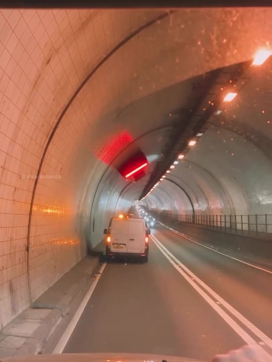 Túnel de azulejos con luz naranja y una furgoneta blanca parada en el carril